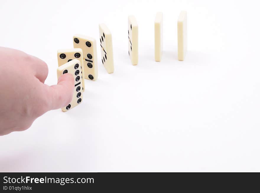 Hand causing dominoes to fall. Hand causing dominoes to fall