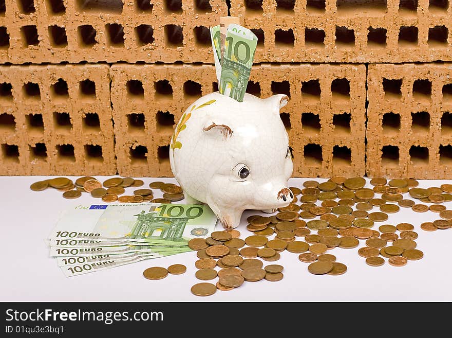 Piggy bank with euros, and bricks in the background