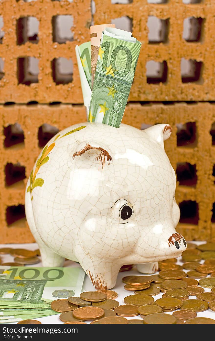 Piggy bank with euros, and bricks in the background