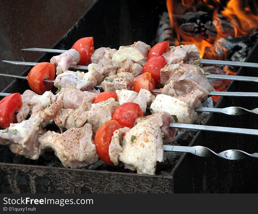 Meat and tomatoes are roasted over hot charcoals. Meat and tomatoes are roasted over hot charcoals