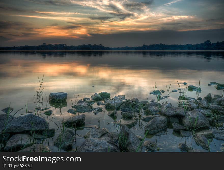 Granite boulders strewn shore of a reservoir seen at sunset