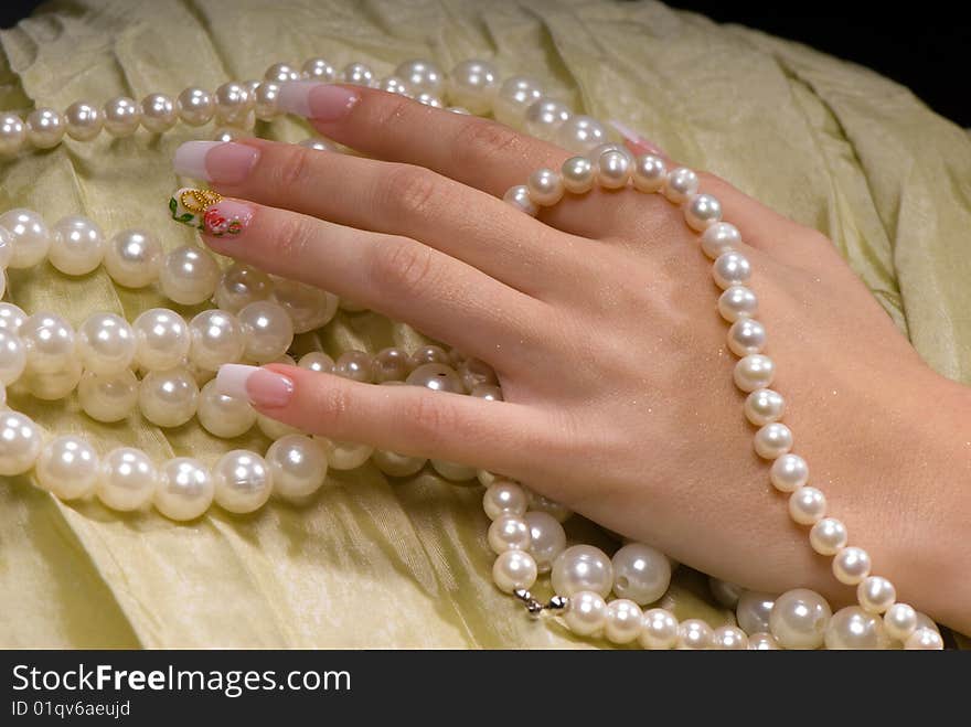 Close-up female hand with a French manicure on a background of bright fabric and zhemchua. Close-up female hand with a French manicure on a background of bright fabric and zhemchua