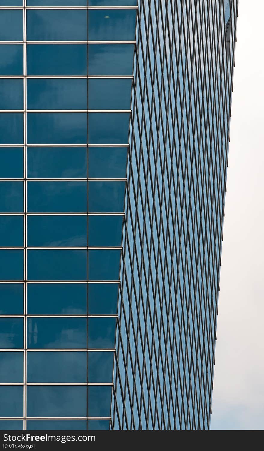 An inward sloping glass wall of a modern building. An inward sloping glass wall of a modern building