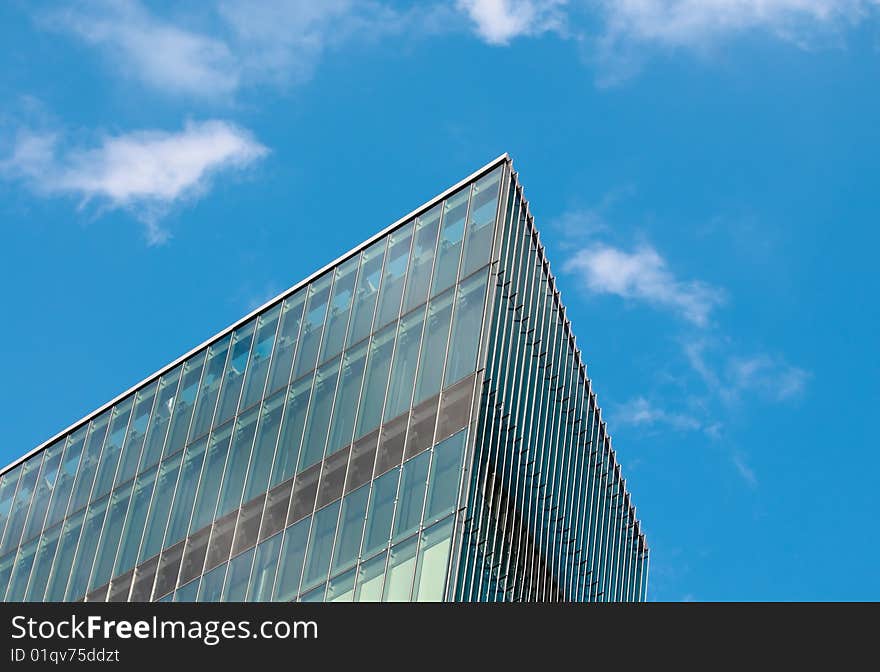 Sharp corner created by the walls of a modern building in a partly cloudy blue sky. Sharp corner created by the walls of a modern building in a partly cloudy blue sky