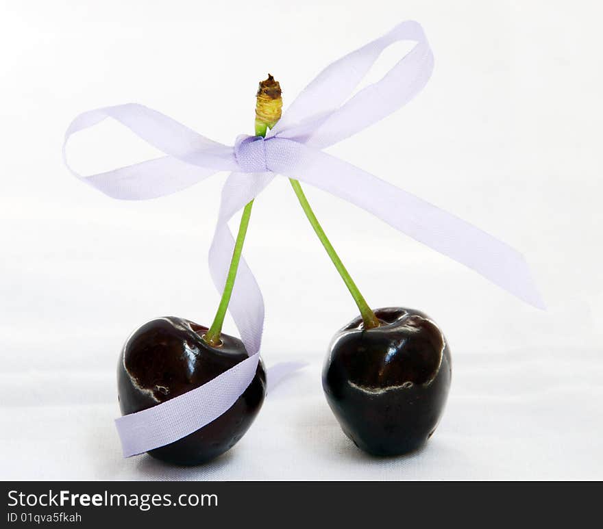 Cherry with a ribbon bow on white background. Cherry with a ribbon bow on white background