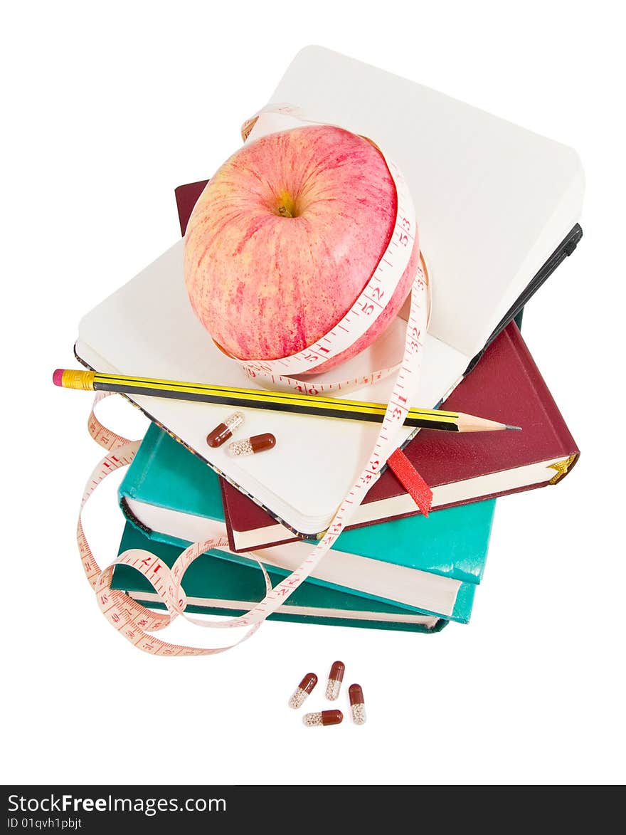 Big ripe apple with measure tape and pills on pile of books as metaphor of healthy eating and diet. Big ripe apple with measure tape and pills on pile of books as metaphor of healthy eating and diet