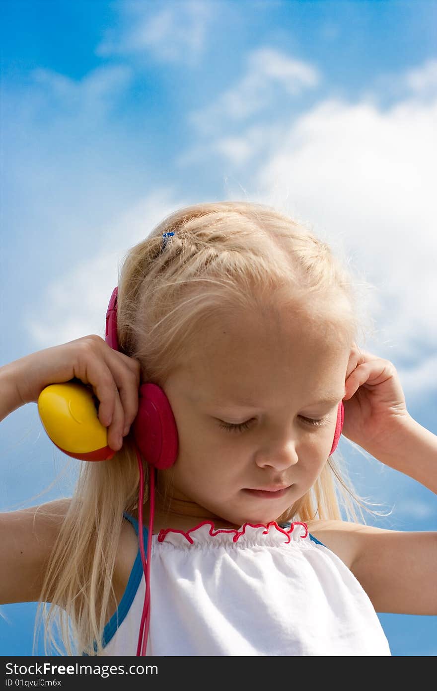 Little blonde girl with closed eyes in red earphones listens mp3 player music outdoor. Little blonde girl with closed eyes in red earphones listens mp3 player music outdoor