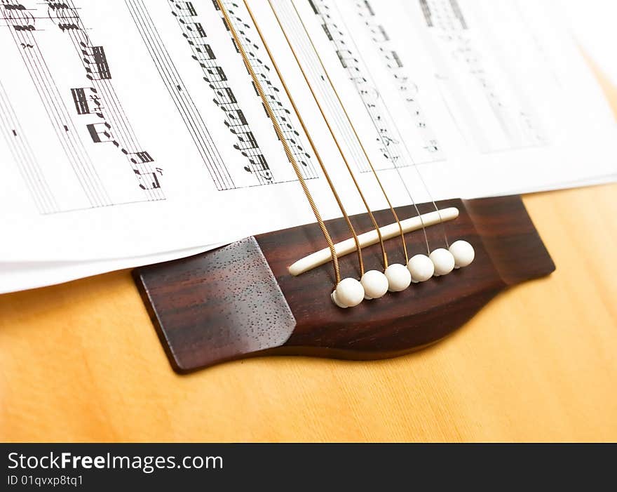 Wooden guitar with six strings on sheets music