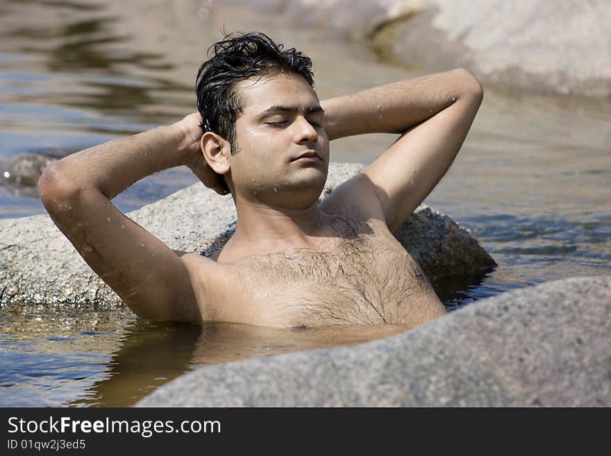 Man having yoga in water between stones