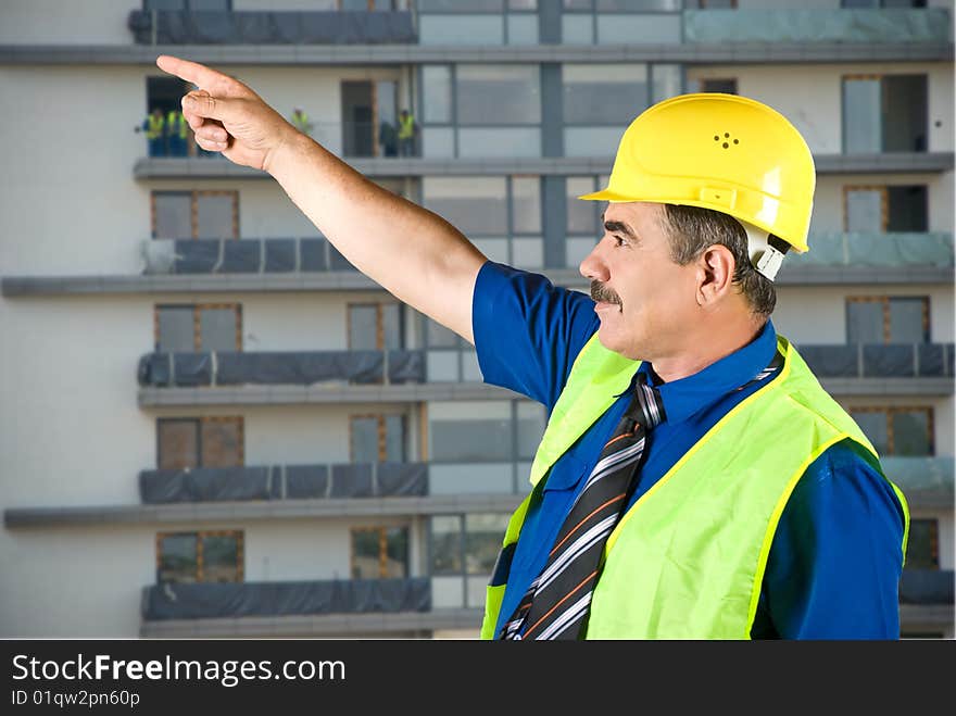 Single mature architect man pointing on site and looking up,construction with workers in background,check out. Single mature architect man pointing on site and looking up,construction with workers in background,check out