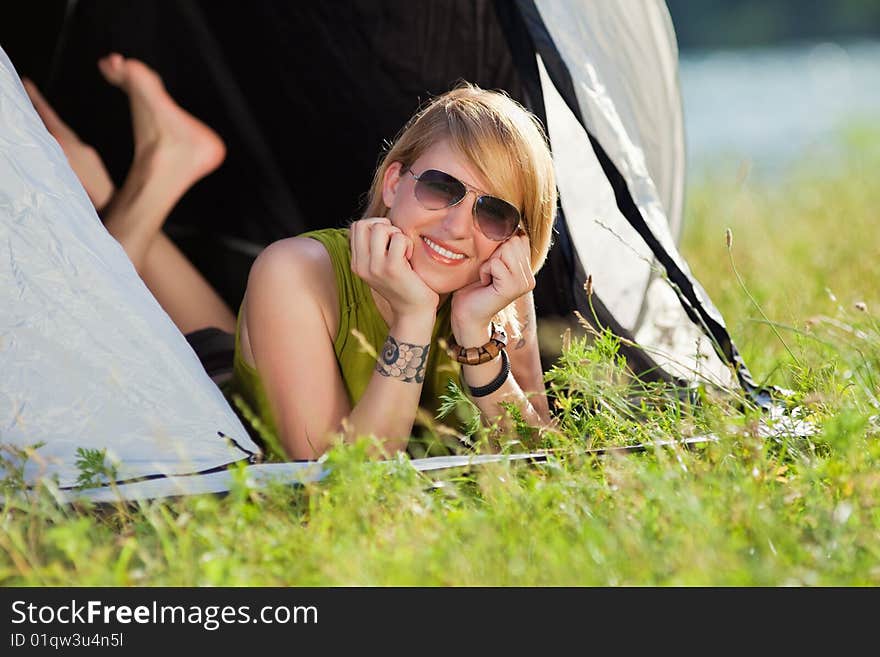 Young blonde woman lying in tent with feet crossed. Young blonde woman lying in tent with feet crossed.