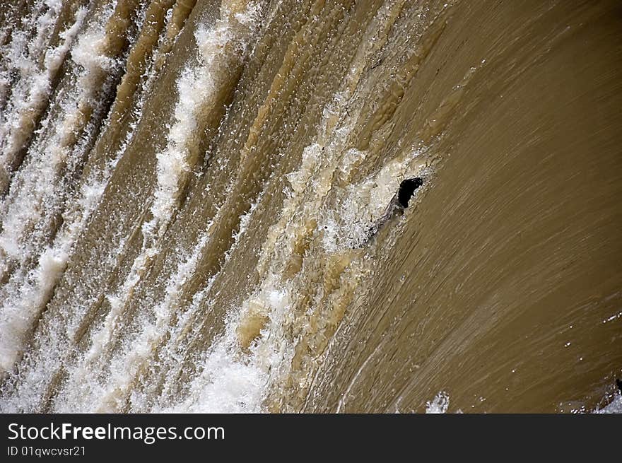 This photo captures a log going over a waterfall in a spring time, muddy raging river. This photo captures a log going over a waterfall in a spring time, muddy raging river.