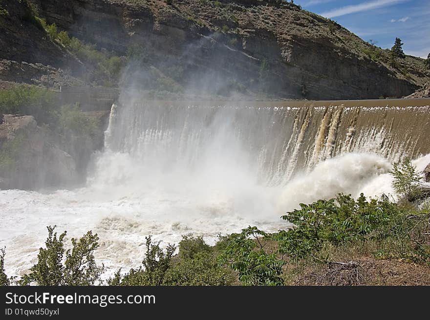 Photo of Enlow Dam in Washington state with desert type mountain, the muddy river going over the fall and mist rising up. Photo of Enlow Dam in Washington state with desert type mountain, the muddy river going over the fall and mist rising up.