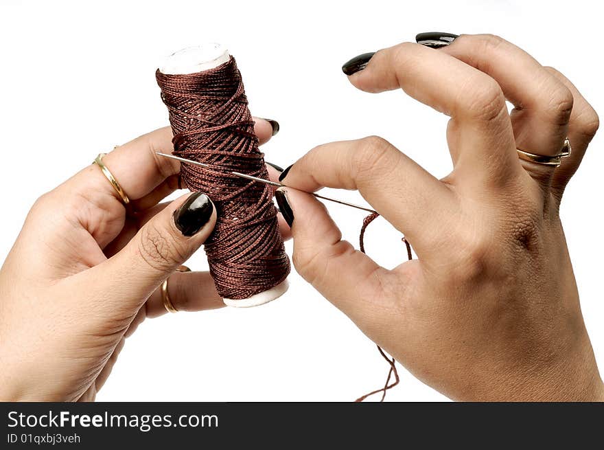 Female hand holding thread spindle and needle.