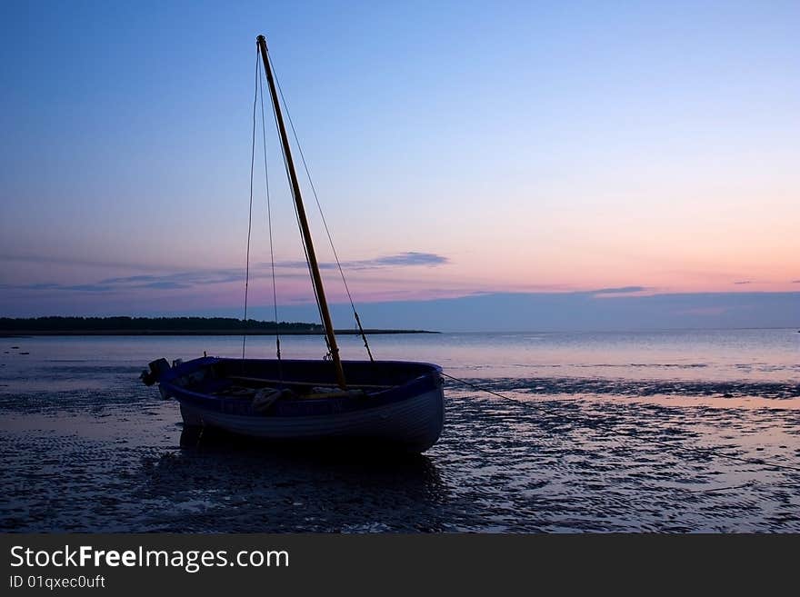 Old sea yacht with the lowered sails on an anchor. The sun, coming in the sea. Old sea yacht with the lowered sails on an anchor. The sun, coming in the sea