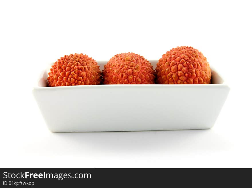 Three lychee in a dish with clipping on a white background