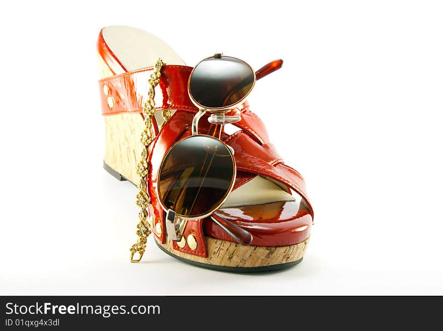 Single red shoe with brown sunglasses and gold bracelet with clipping path on a white background. Single red shoe with brown sunglasses and gold bracelet with clipping path on a white background