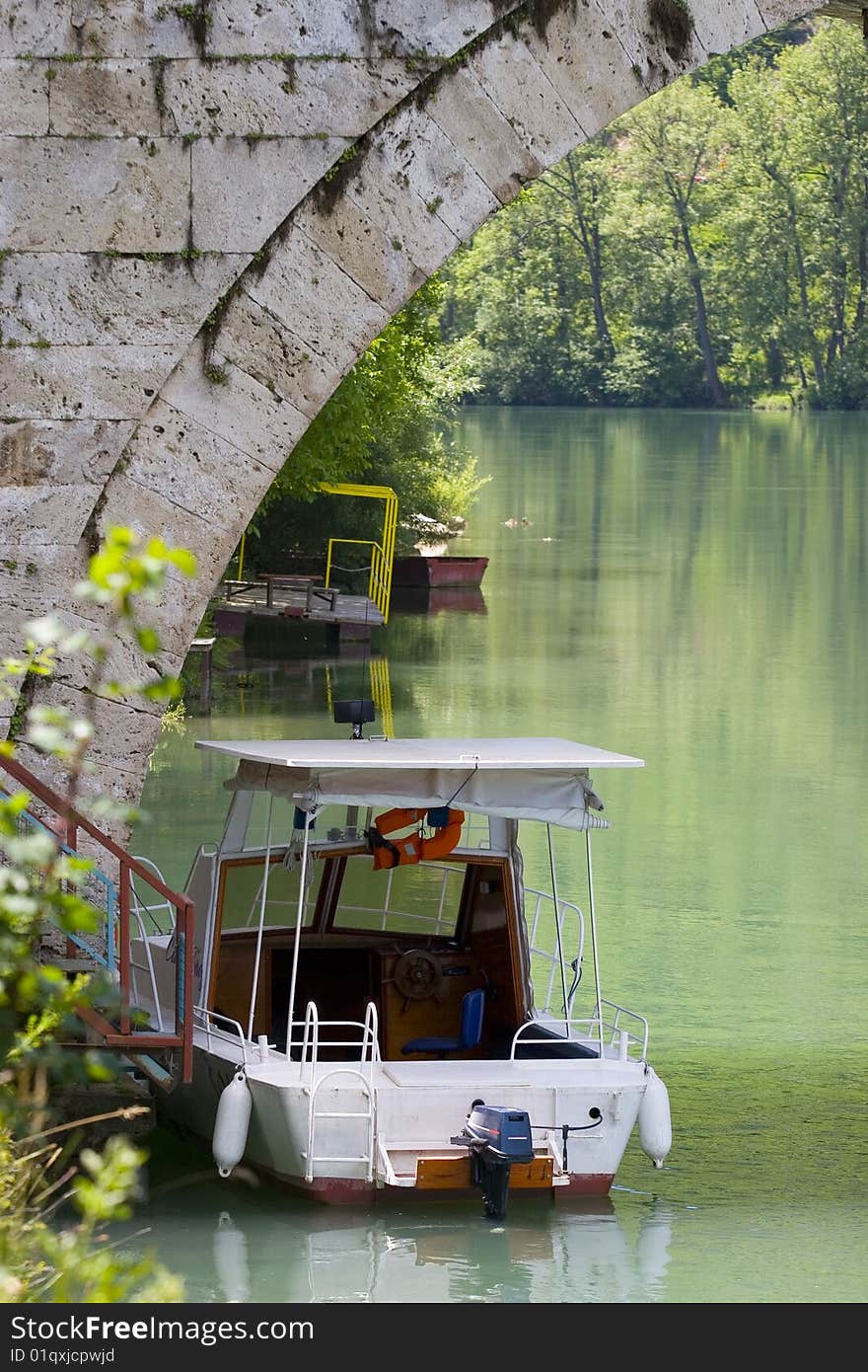 A small boat under an old stone bridge. A small boat under an old stone bridge