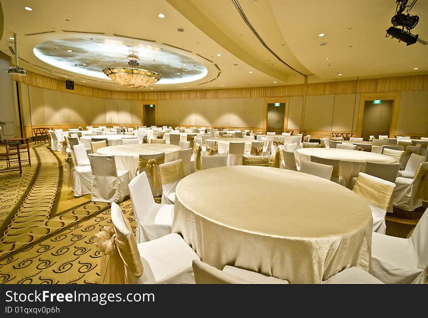 A luxurious banquet room being prepared for an upcoming event, filled with tables and chairs.