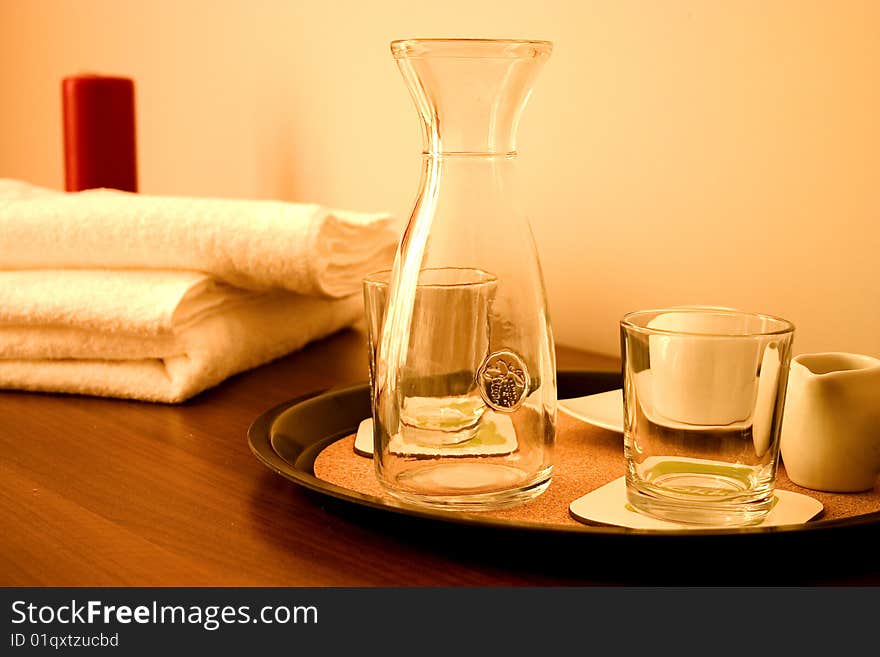 Closeup of nightstand with two red candle, towel and glasses.