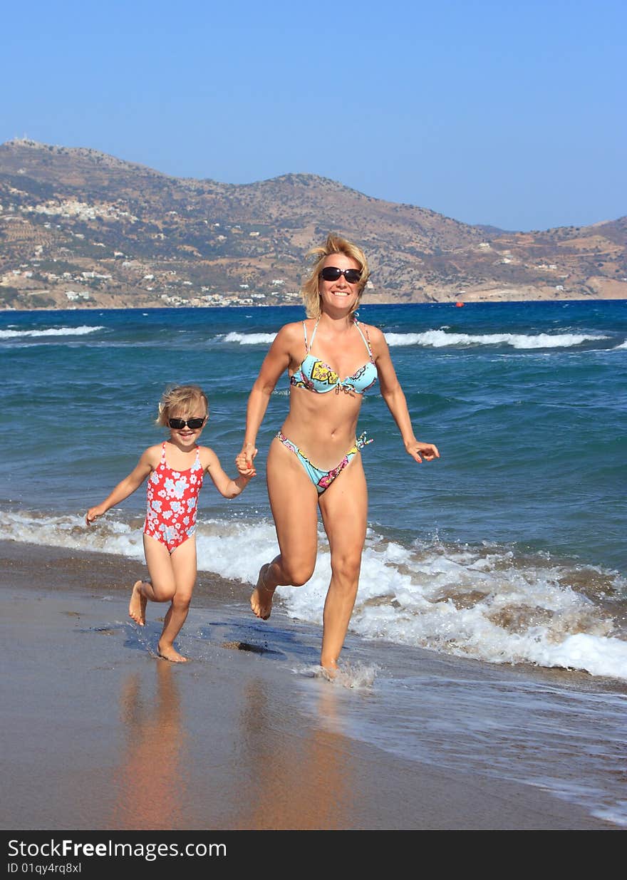 Mother and daughter running on beach