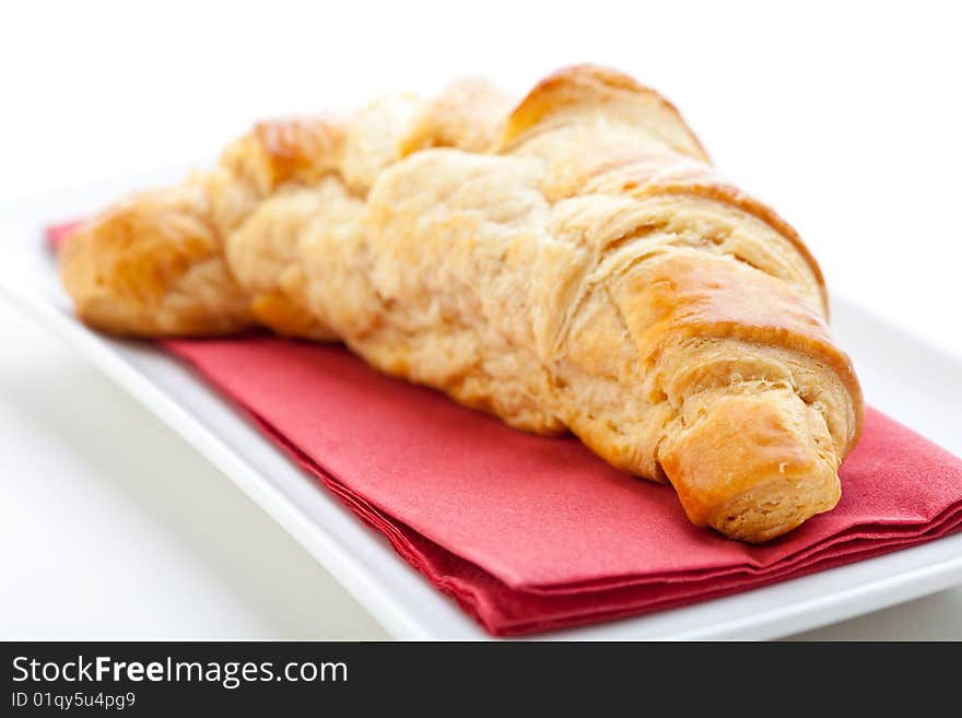 Delicious freshly baked croissant on a white plate with a red napkin