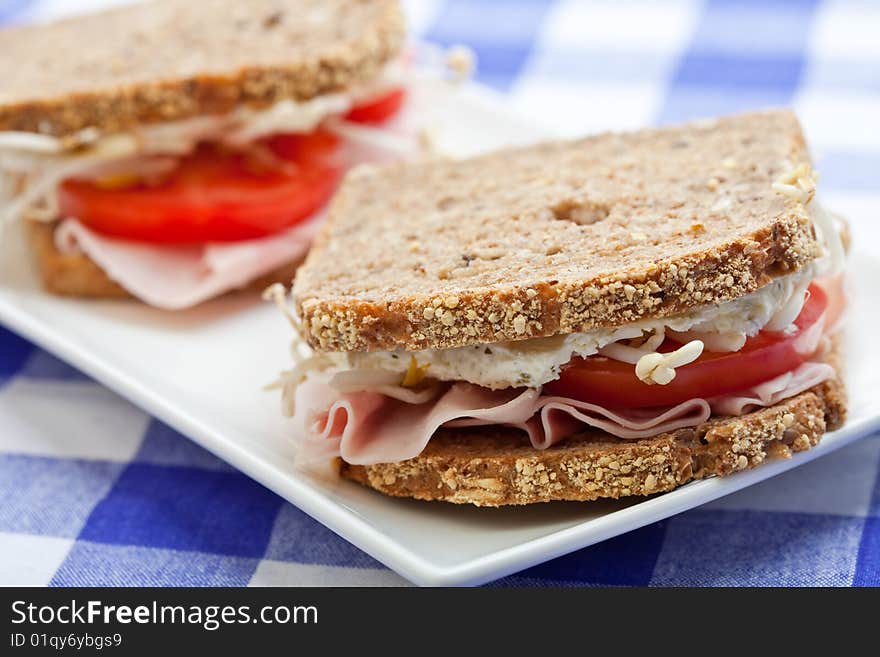 Healthy ham, cheese and tomato sandwich on a white plate