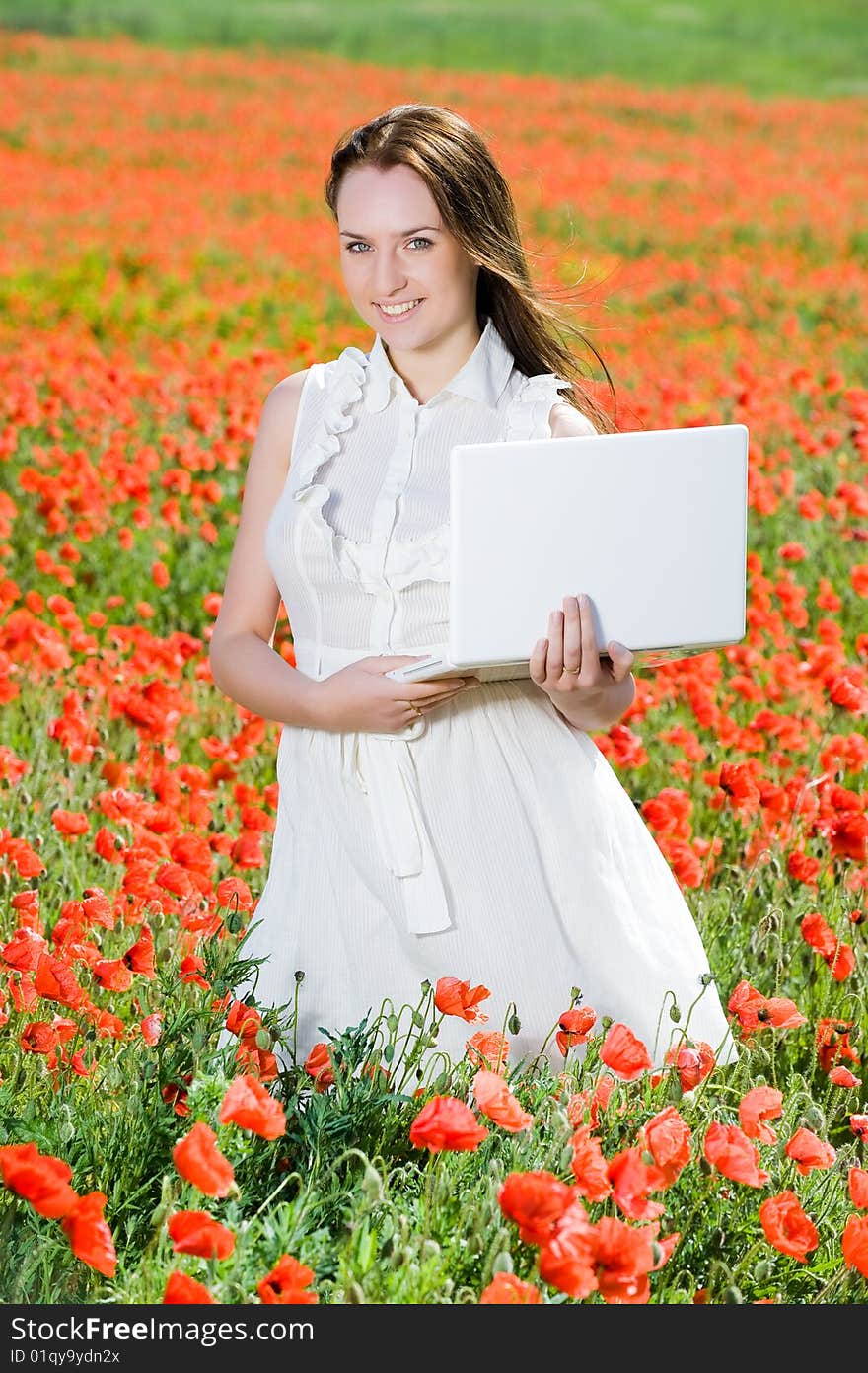 Smiling beautiful girl with laptop in the poppy field