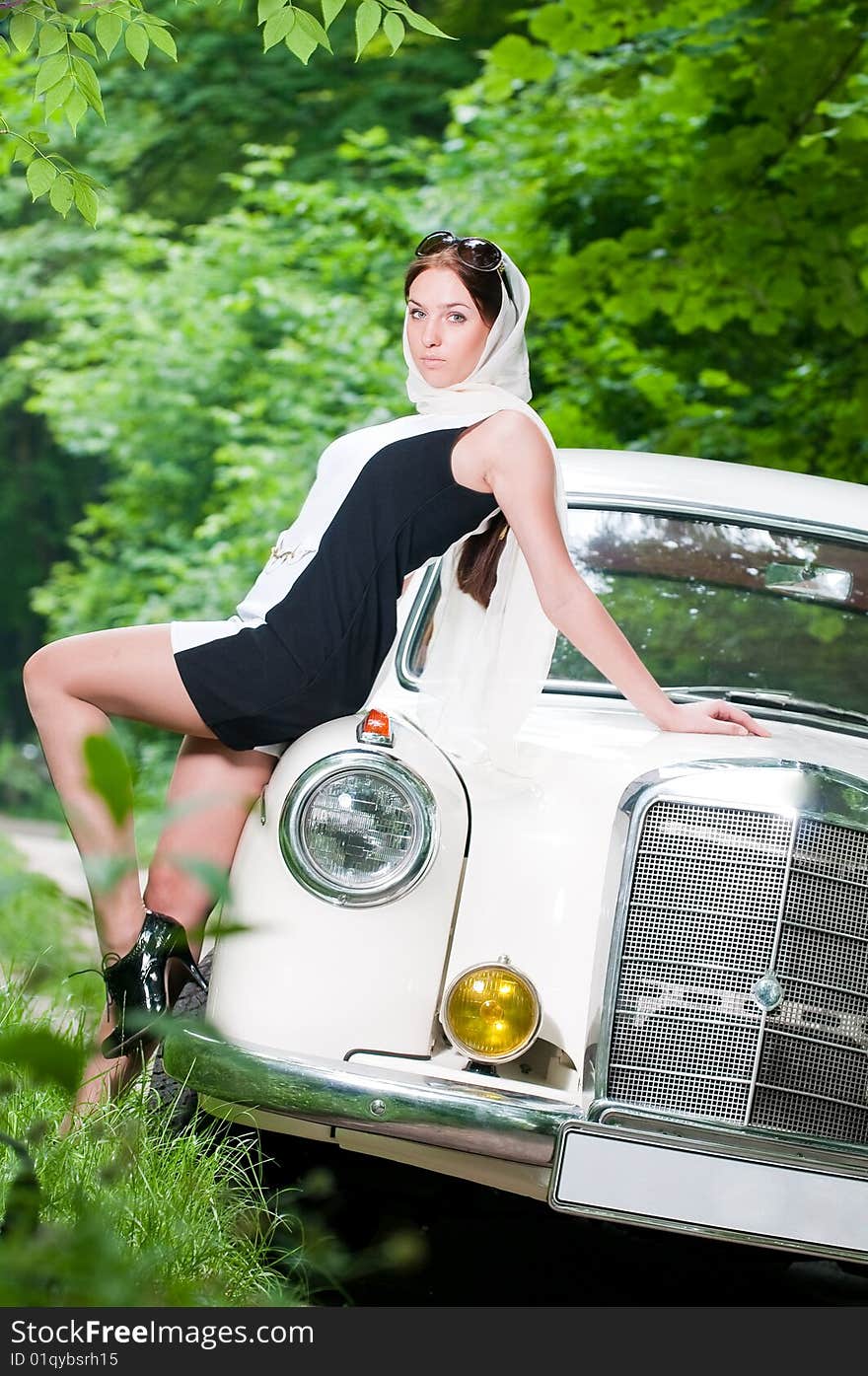 Beautiful pin-up girl sitting on retro car