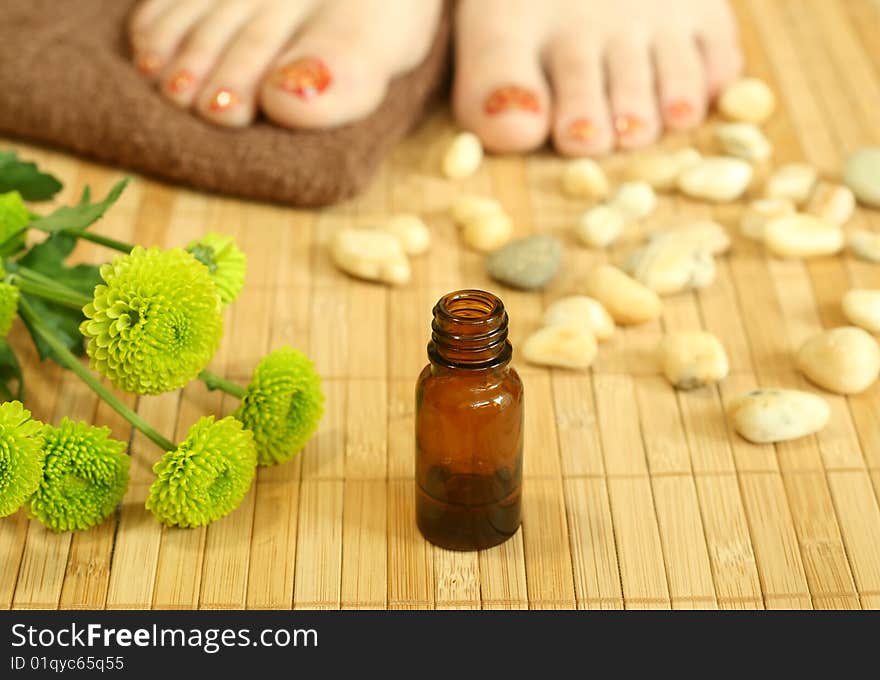 Bottle of massage  oil, stones and female legs. Bottle of massage  oil, stones and female legs