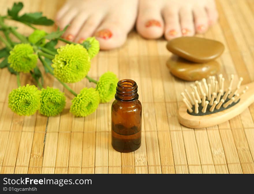 Bottle of massage oil, stones and female legs. Bottle of massage oil, stones and female legs