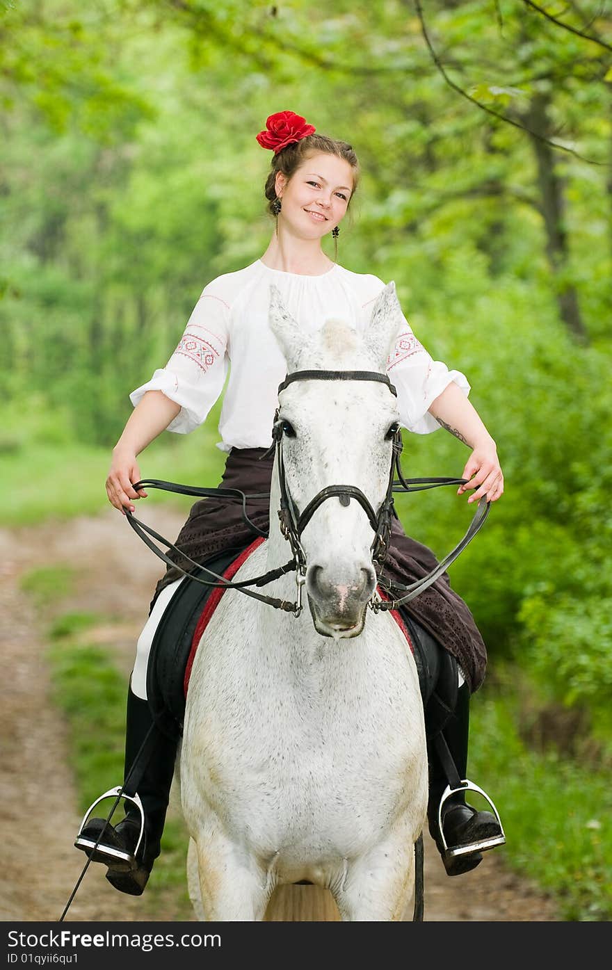 Smiling girl riding horse in the forest