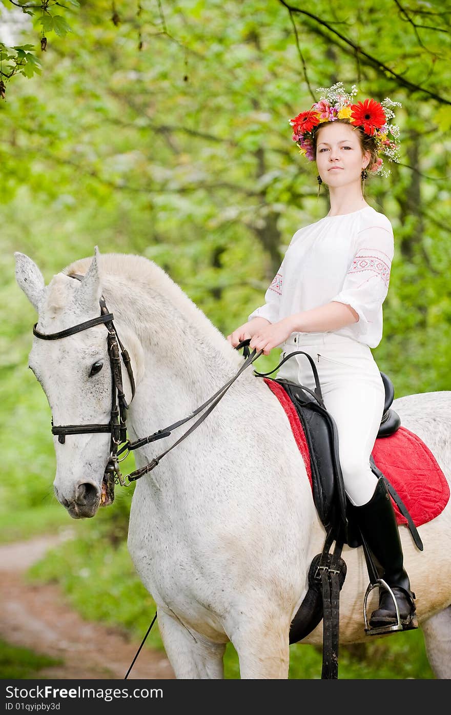 Beautiful girl in floral wreath riding horse