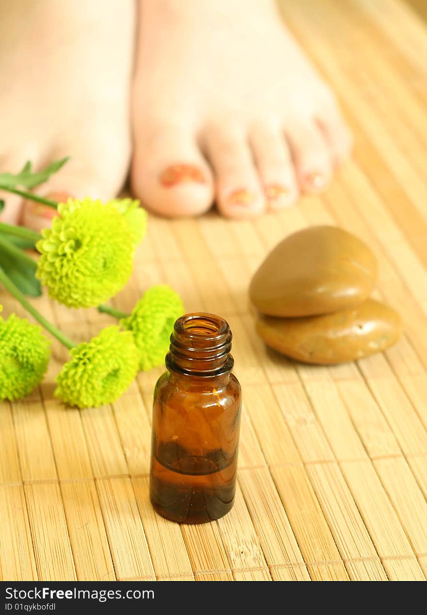 Bottle of massage oil, stones and female legs. Bottle of massage oil, stones and female legs