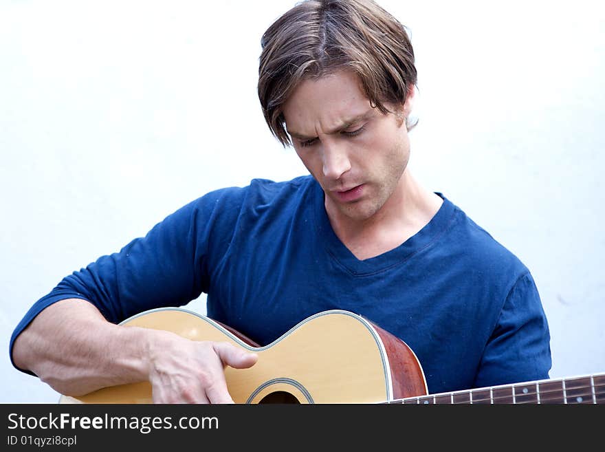 An attractive guitar player with a blue shirt and white backround