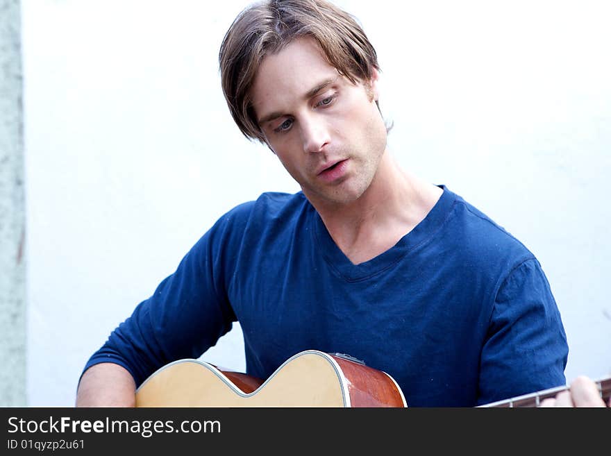 An attractive guitar player with a blue shirt and white backround