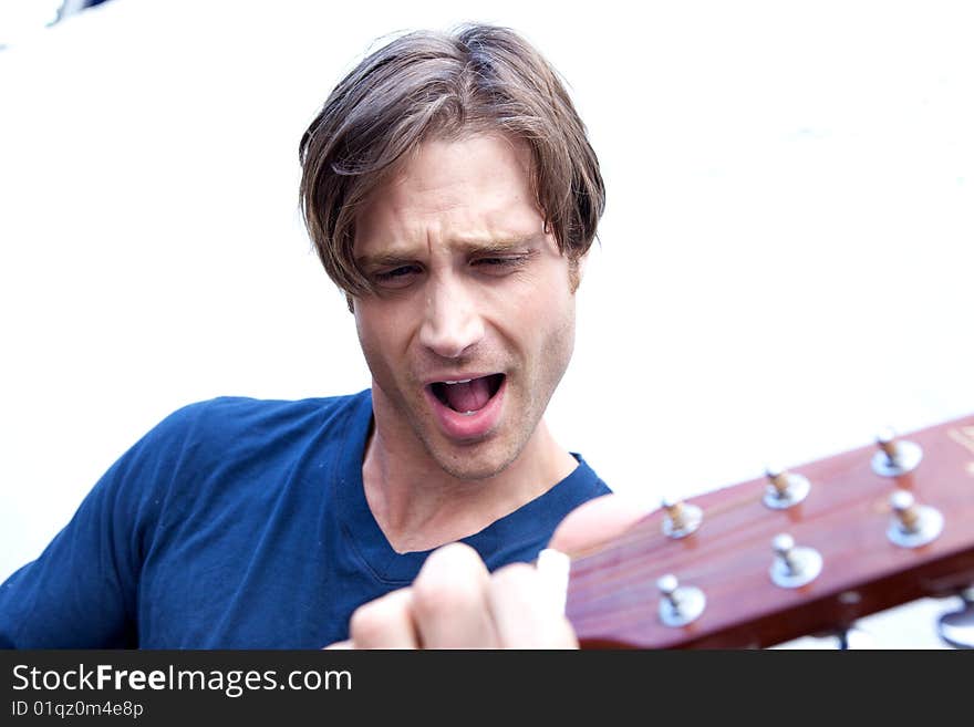 An attractive guitar player with a blue shirt and white backround