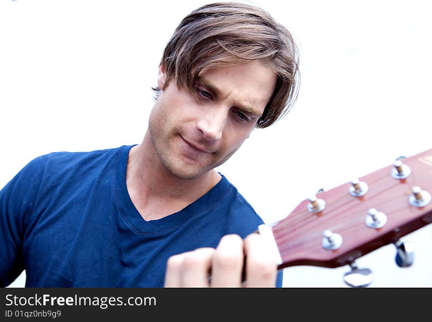 An attractive guitar player with a blue shirt and white background