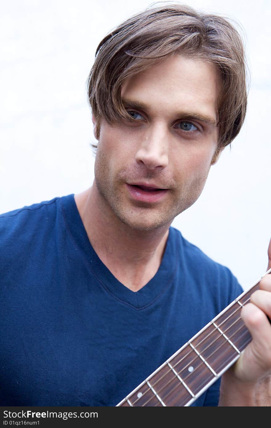 An attractive guitar player with a blue shirt and white backround