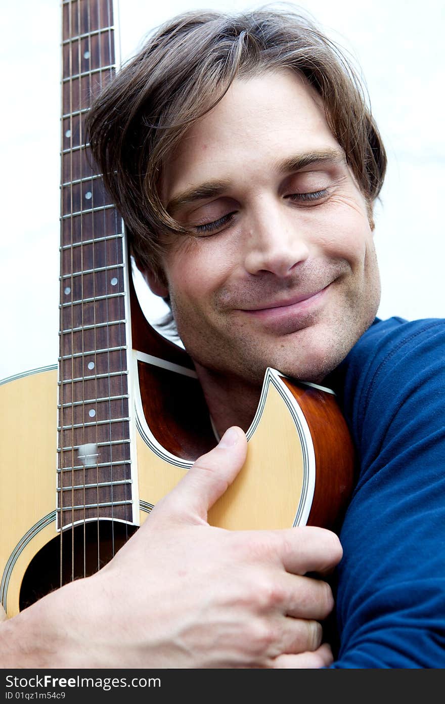 An attractive guitar player with a blue shirt and white background