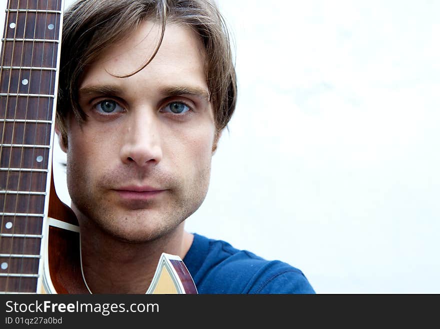 An attractive guitar player with a blue shirt and white backround