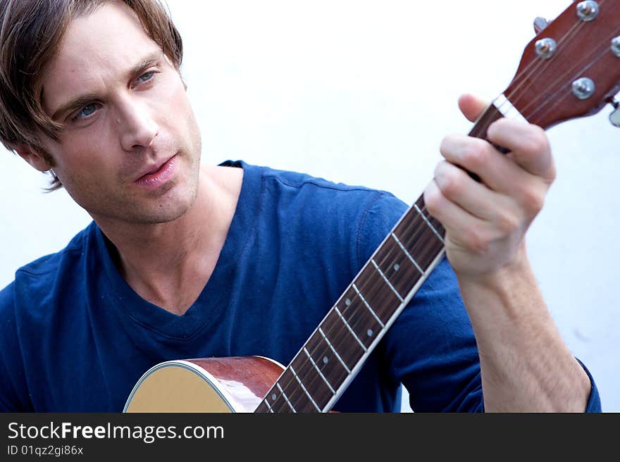 An attractive guitar player with a blue shirt and white backround