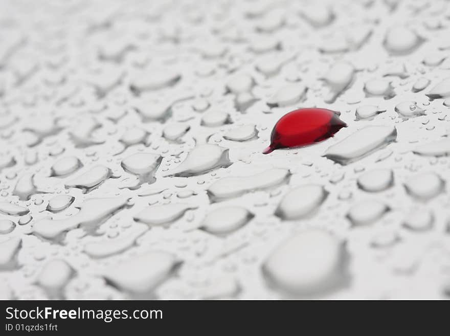 Drop of raspberry juice among drops of water