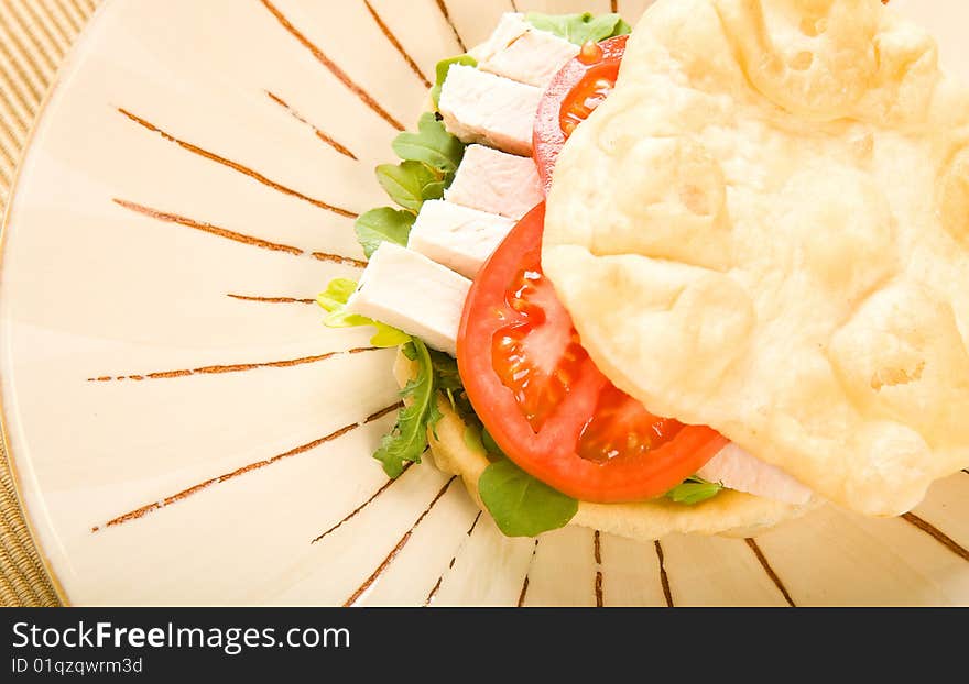 Roasted chicken on buttery flat bread with lettuce and tomato. Roasted chicken on buttery flat bread with lettuce and tomato