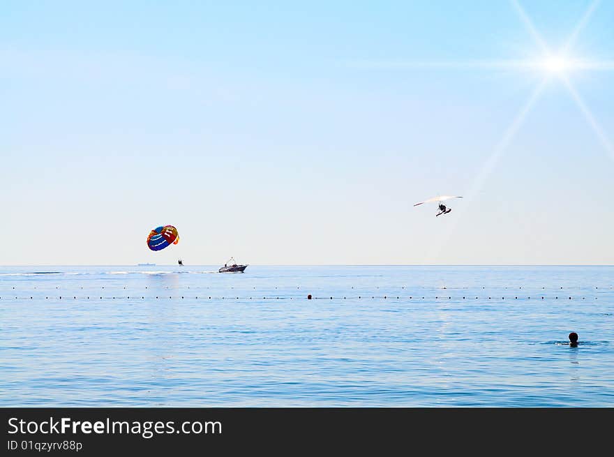 Some man are parasailing over the sea next to seaplane. Some man are parasailing over the sea next to seaplane.