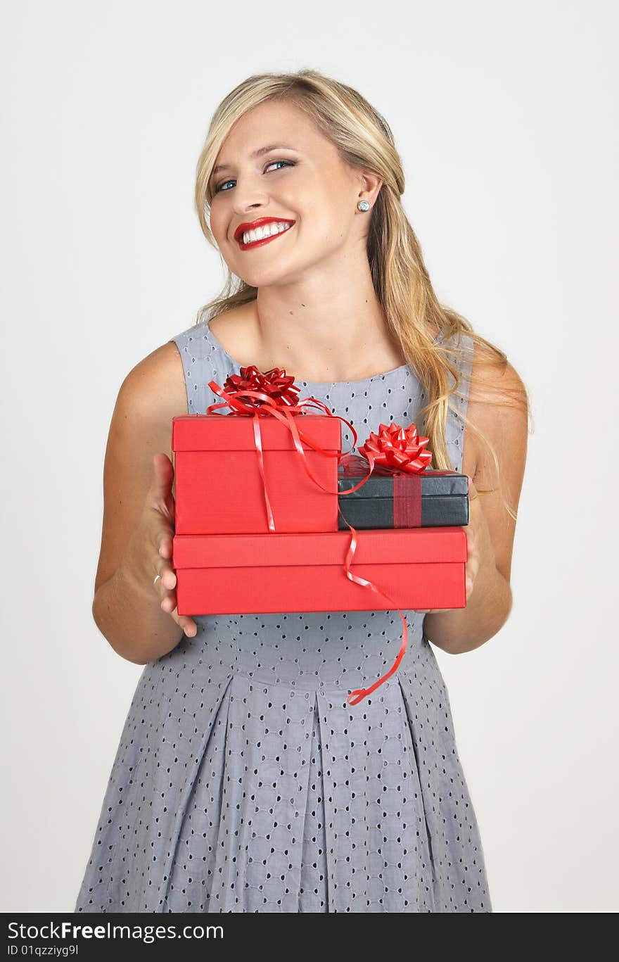 Portrait of a beautiful blonde woman with light blue eyes and evening make-up holding gift boxes on grey background. Portrait of a beautiful blonde woman with light blue eyes and evening make-up holding gift boxes on grey background