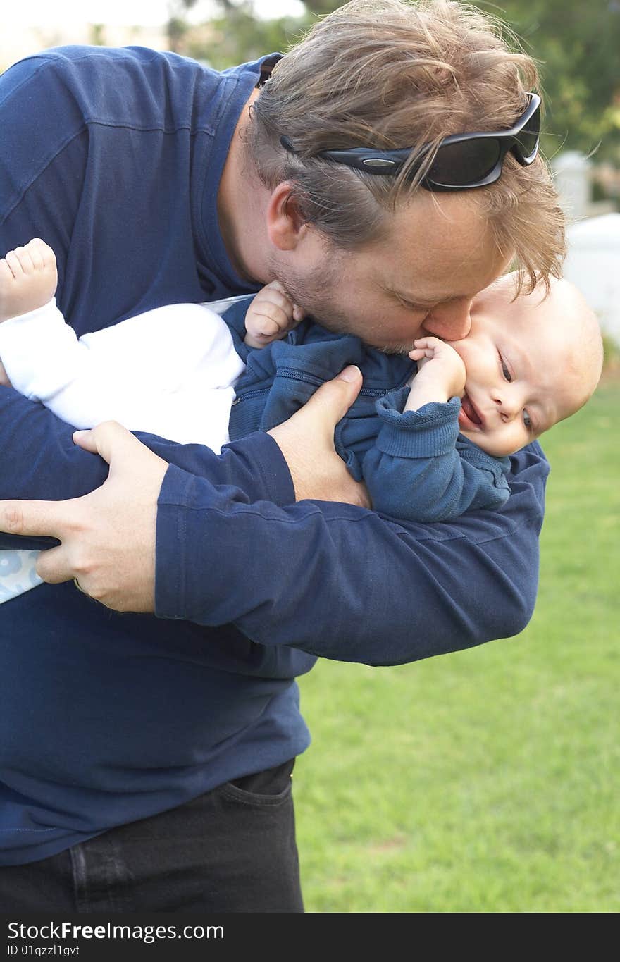 Young father kissing his small son. Focus is on the father. Young father kissing his small son. Focus is on the father