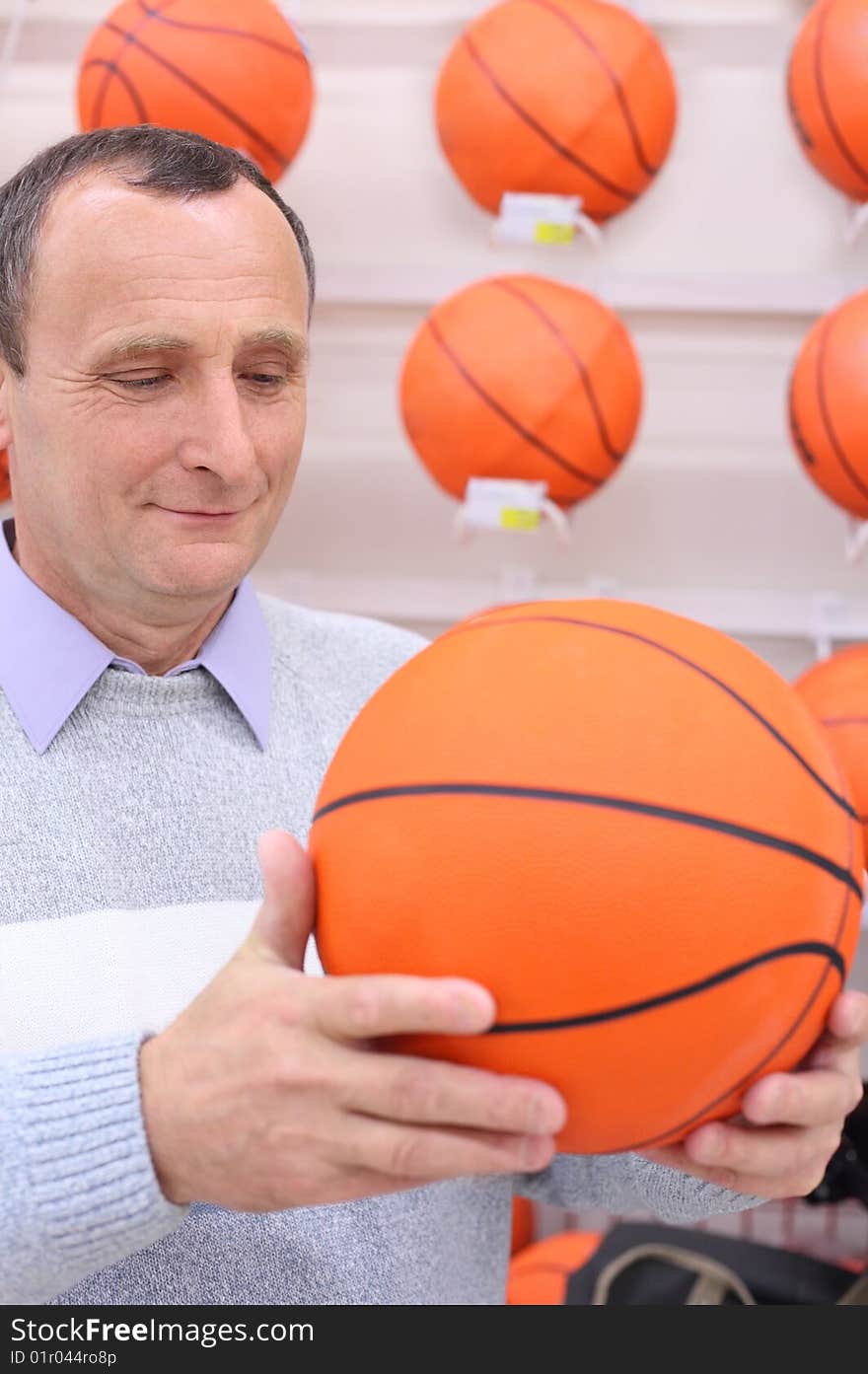 Elderly man in shop with basketball ball in hands. Elderly man in shop with basketball ball in hands