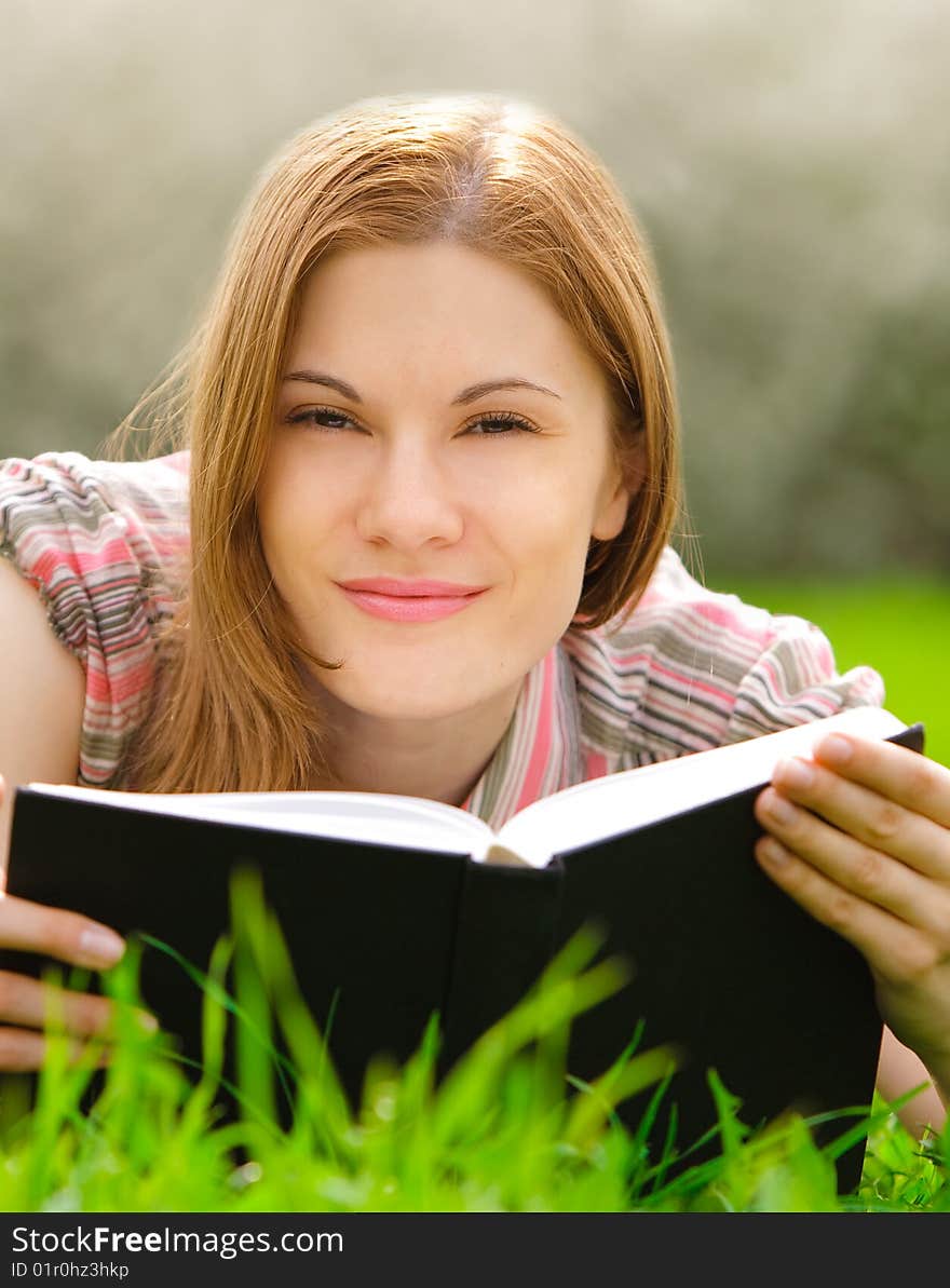 Attractive young woman reading outdoors. Attractive young woman reading outdoors