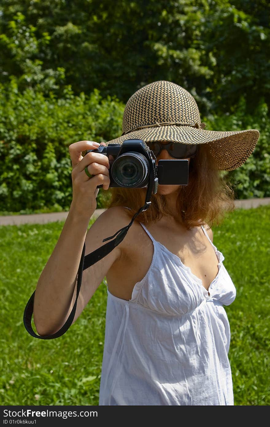 Girl in hat and white skirt holding digital camera in front of her face. Girl in hat and white skirt holding digital camera in front of her face